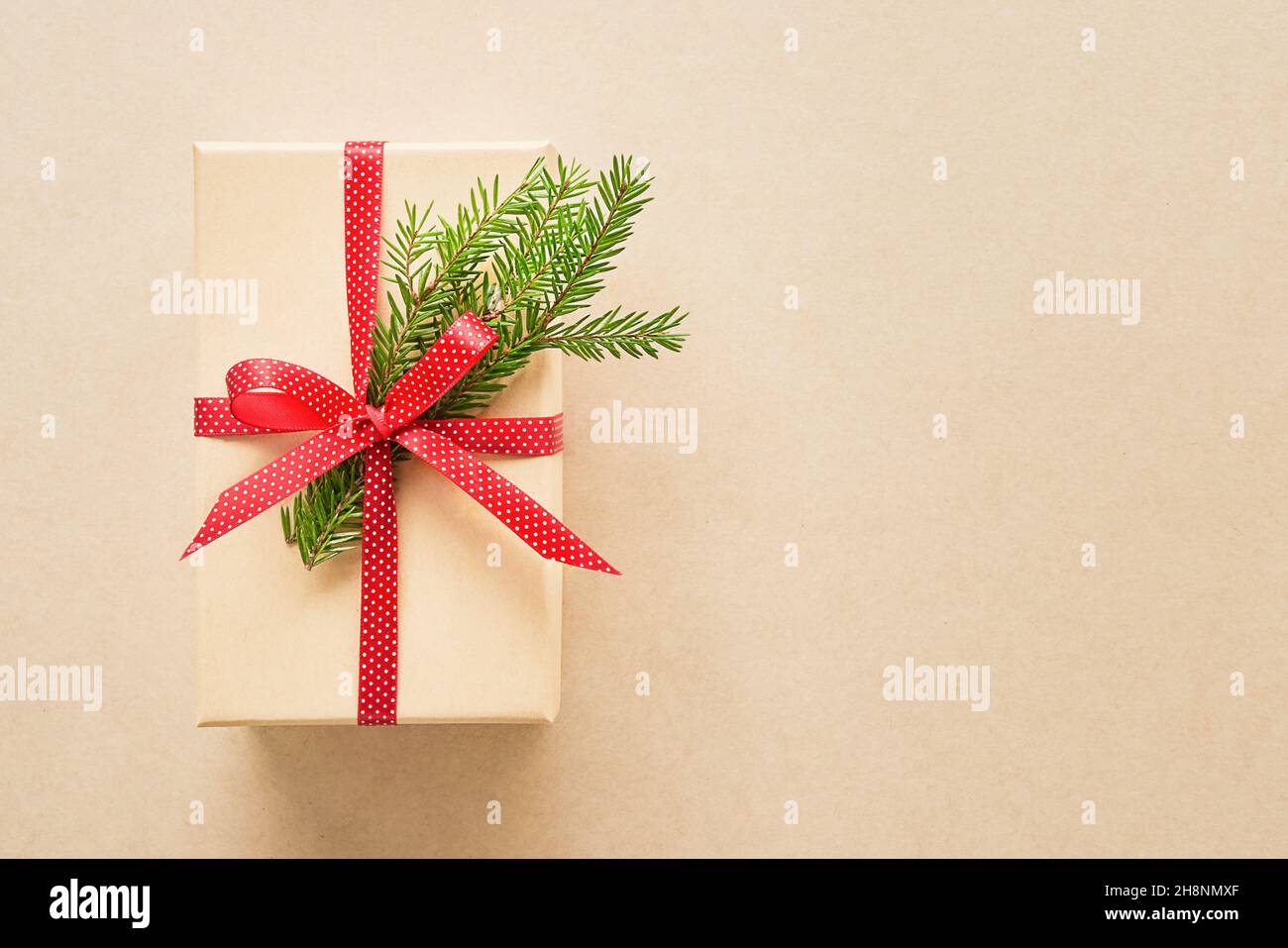Weihnachts-Geschenkbox mit rotem Band und Tannenzweig auf einem Kraftpapier Hintergrund dekoriert. Draufsicht, Platz für Text kopieren Stockfoto