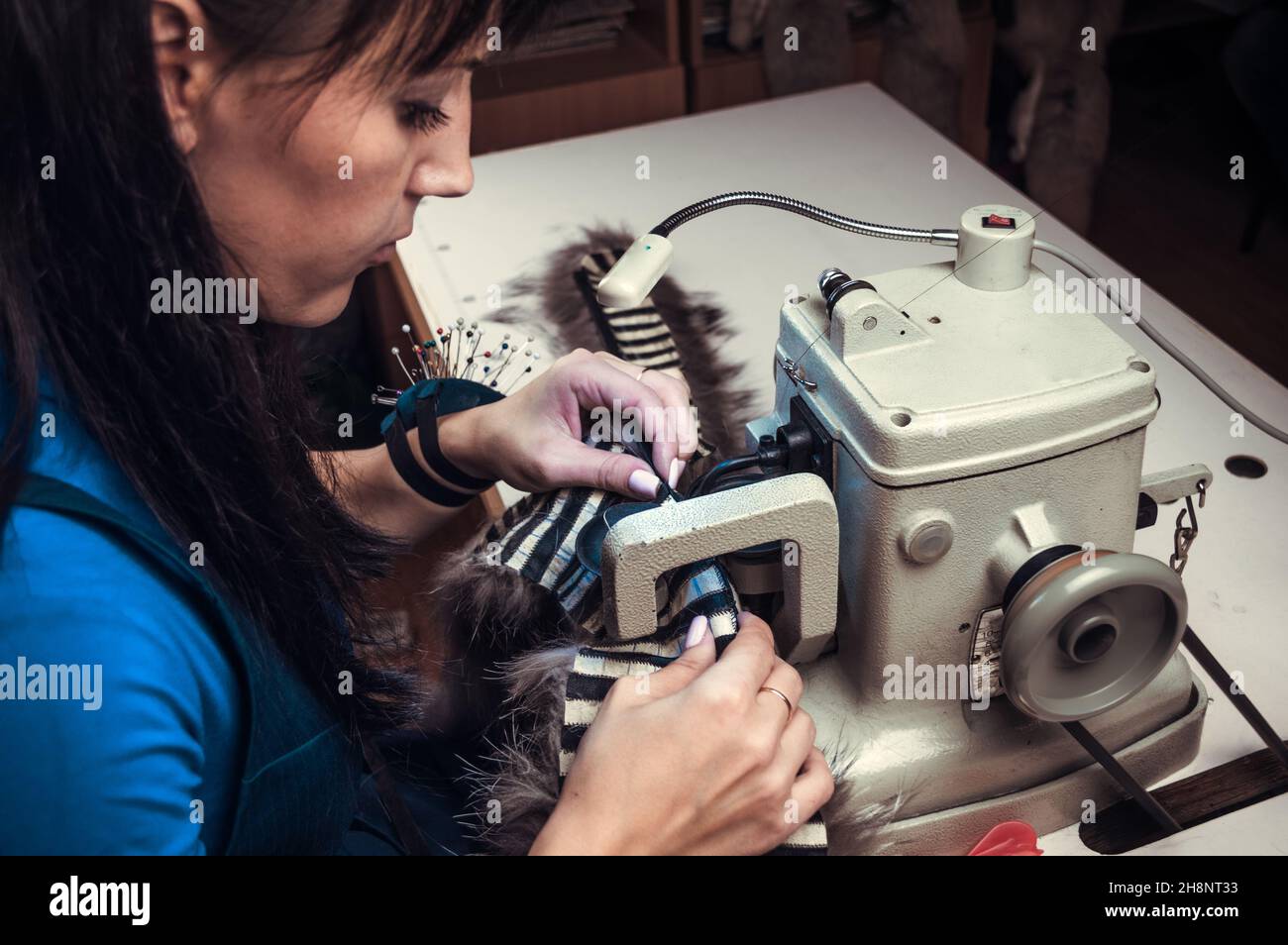 Frau Schneidermeisterin, die das Fell an die Maschine des Kürzers näht Stockfoto