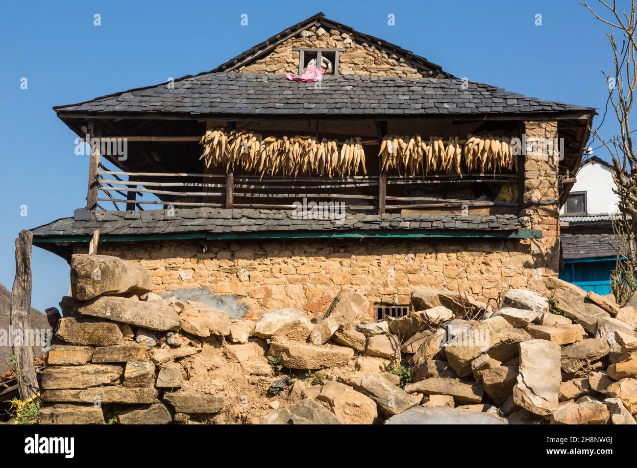 Ein traditionelles Bauernhaus aus Stein mit Ähren aus Mais, die unter den Traufen im Newari-Dorf Bandipur, Nepal, trocknen. Stockfoto