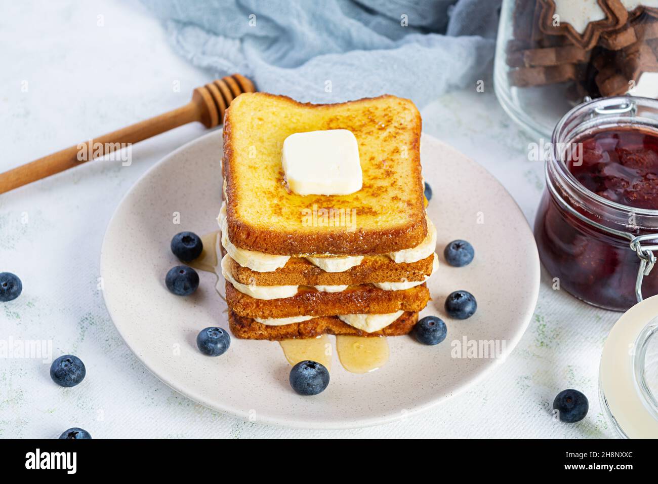 French Toast mit Banane, Heidelbeere, Honig und Erdbeermarmelade. Köstliches Frühstück oder Brunch mit Toast und Keksen Stockfoto