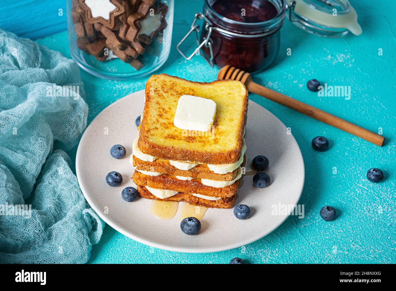 French Toast mit Banane, Heidelbeere, Honig und Erdbeermarmelade. Köstliches Frühstück oder Brunch mit Toast und Keksen Stockfoto