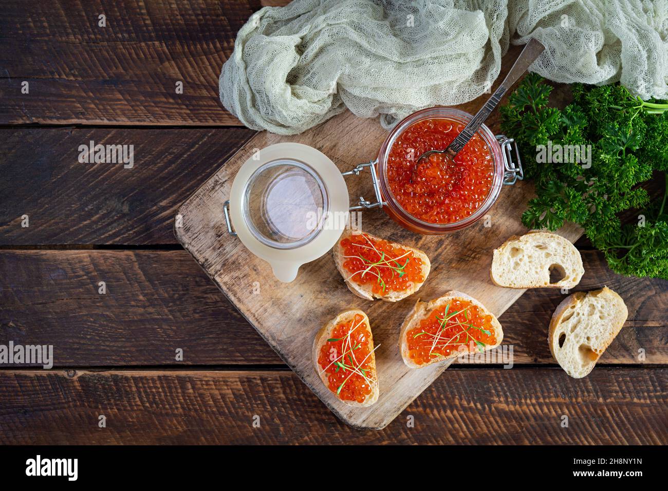 Köstlicher frischer roter Kaviar mit Baguette-Toasts auf Holzhintergrund. Draufsicht Stockfoto