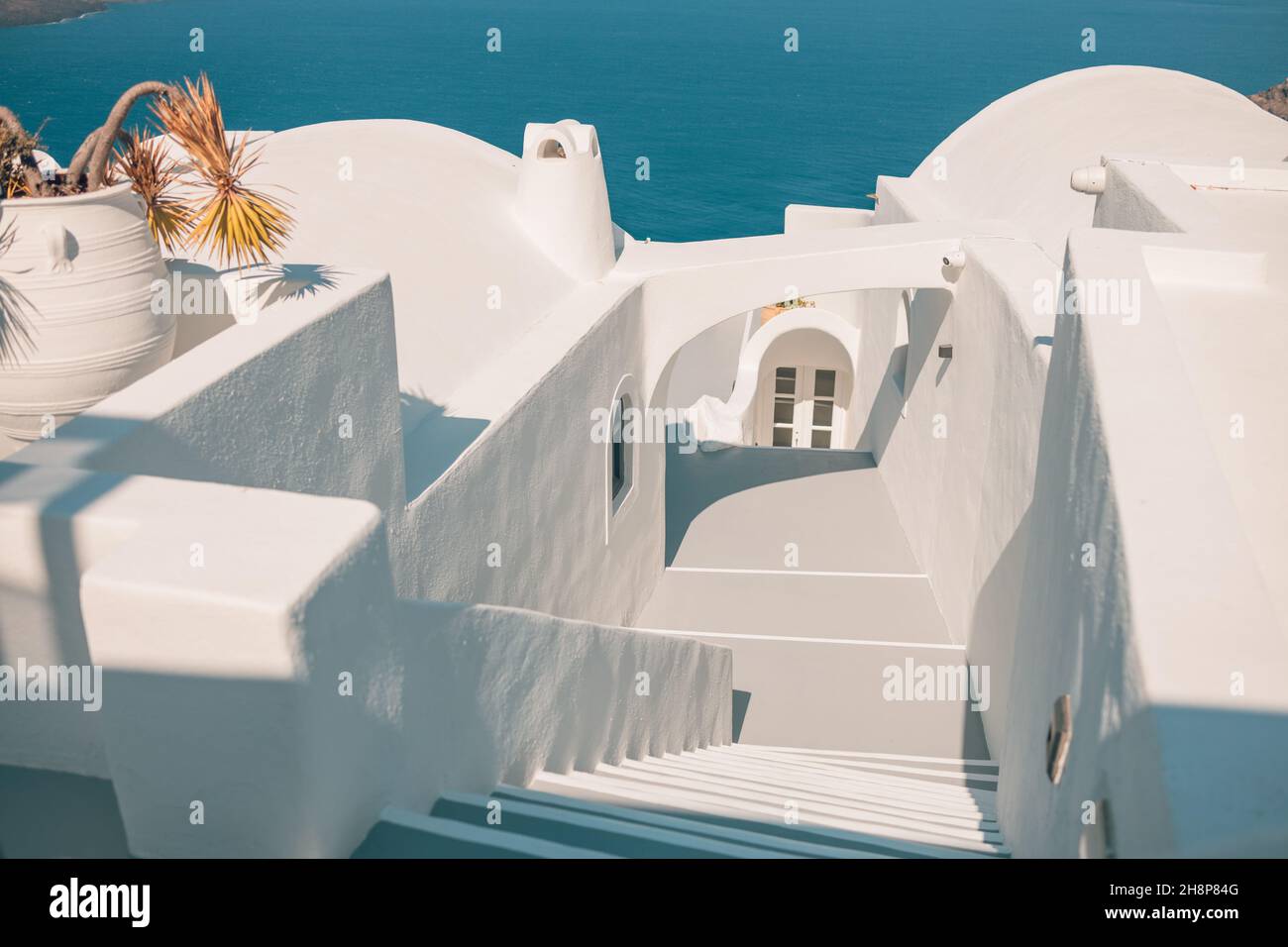 Minimaler Hintergrund aus weißen Steinen Treppe zwischen weißen Wänden, Oia, Santorini, Griechenland. Idyllisch, romantisch, landschaftlich reizvoll, Blick auf die Caldera der Ägäis. Reisen Stockfoto