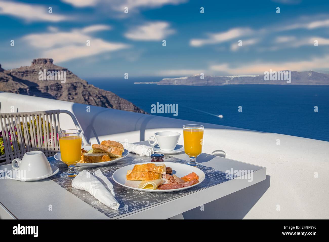 Morgens frischer Saft und Frühstück mit Blick auf das blaue Meer. Pärchen reisen und Hochzeitsreise, idyllischer Morgen landschaftlich schöner Blick auf die Caldera in Griechenland Stockfoto