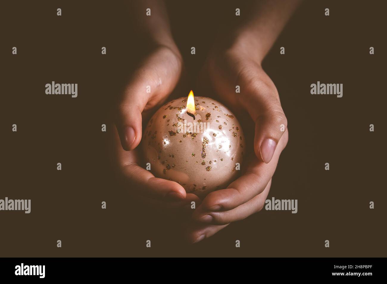 Hände mit Weihnachtskerze auf Schwarz, Symbol für Glauben und Religion Stockfoto