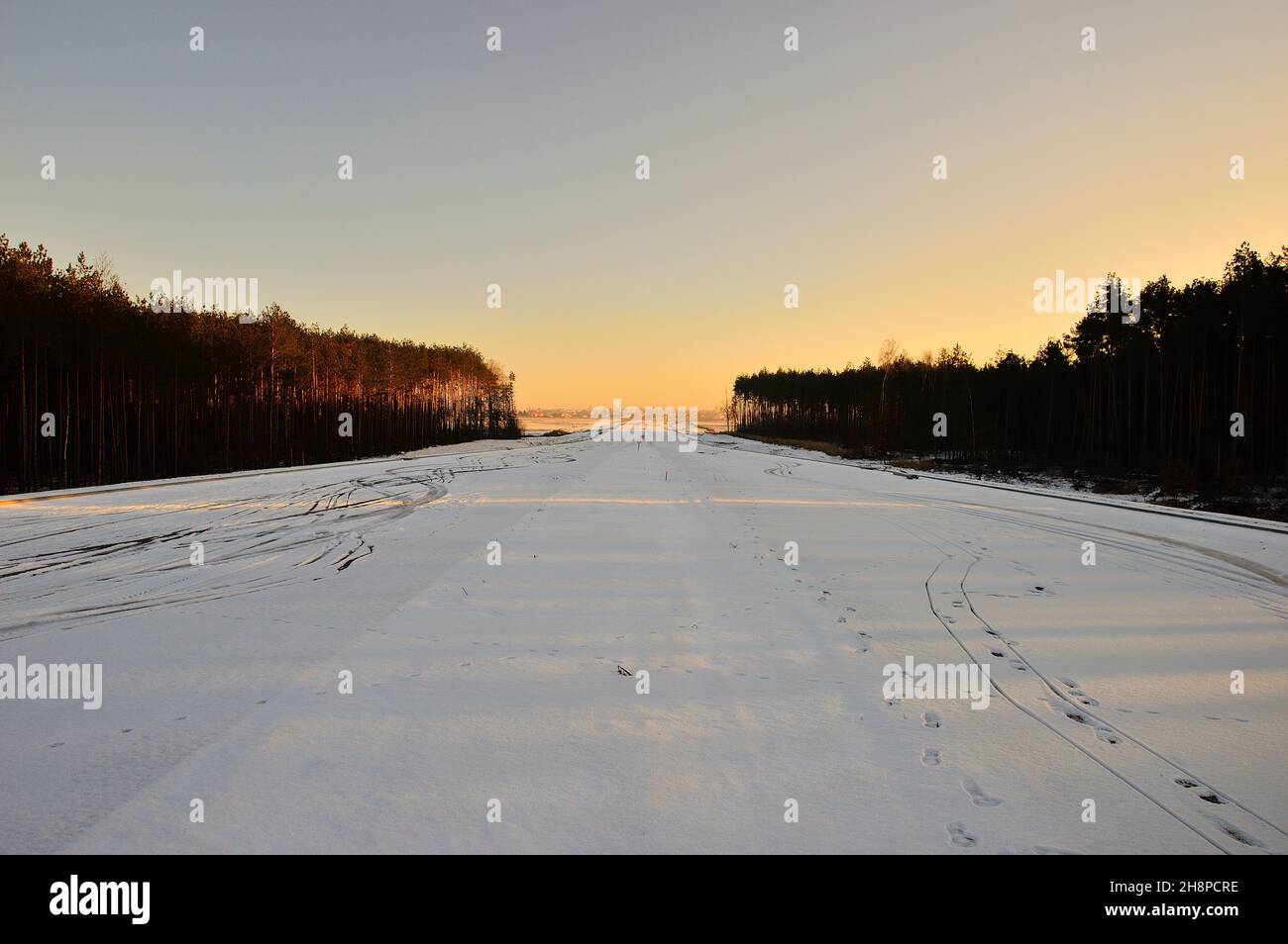 Schneebedecktes Feld zwischen Wäldern am Rand des Rahmens. Winter. Stockfoto