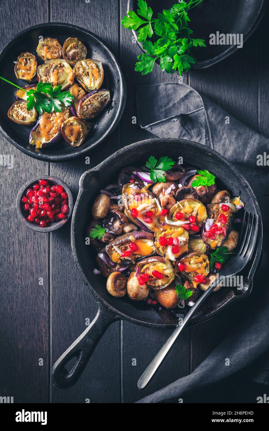 Gebackene kleine Auberginen, gefüllt mit Pilzen und Granatapfel in einer Backform Stockfoto