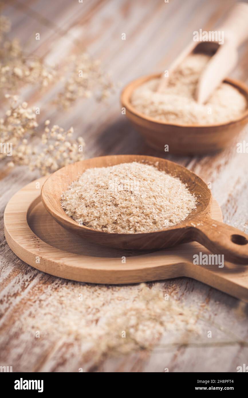 Haufen Flohschalen in Holzschüssel auf Holztisch. Die Psylliumschale, auch Isabgol genannt, ist eine Faser, die aus den Samen der Plantago ovata Pflanze stammt Stockfoto