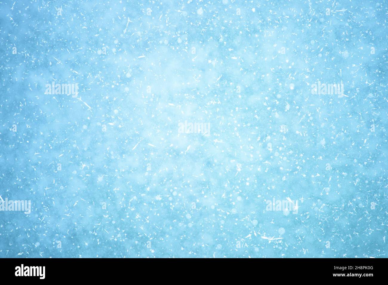 Leuchtendes, natürlich blaues Eis mit einem Dunseffekt mit weißen Frostflecken und gefrorenen Luftblasen. Hintergrund. Stockfoto