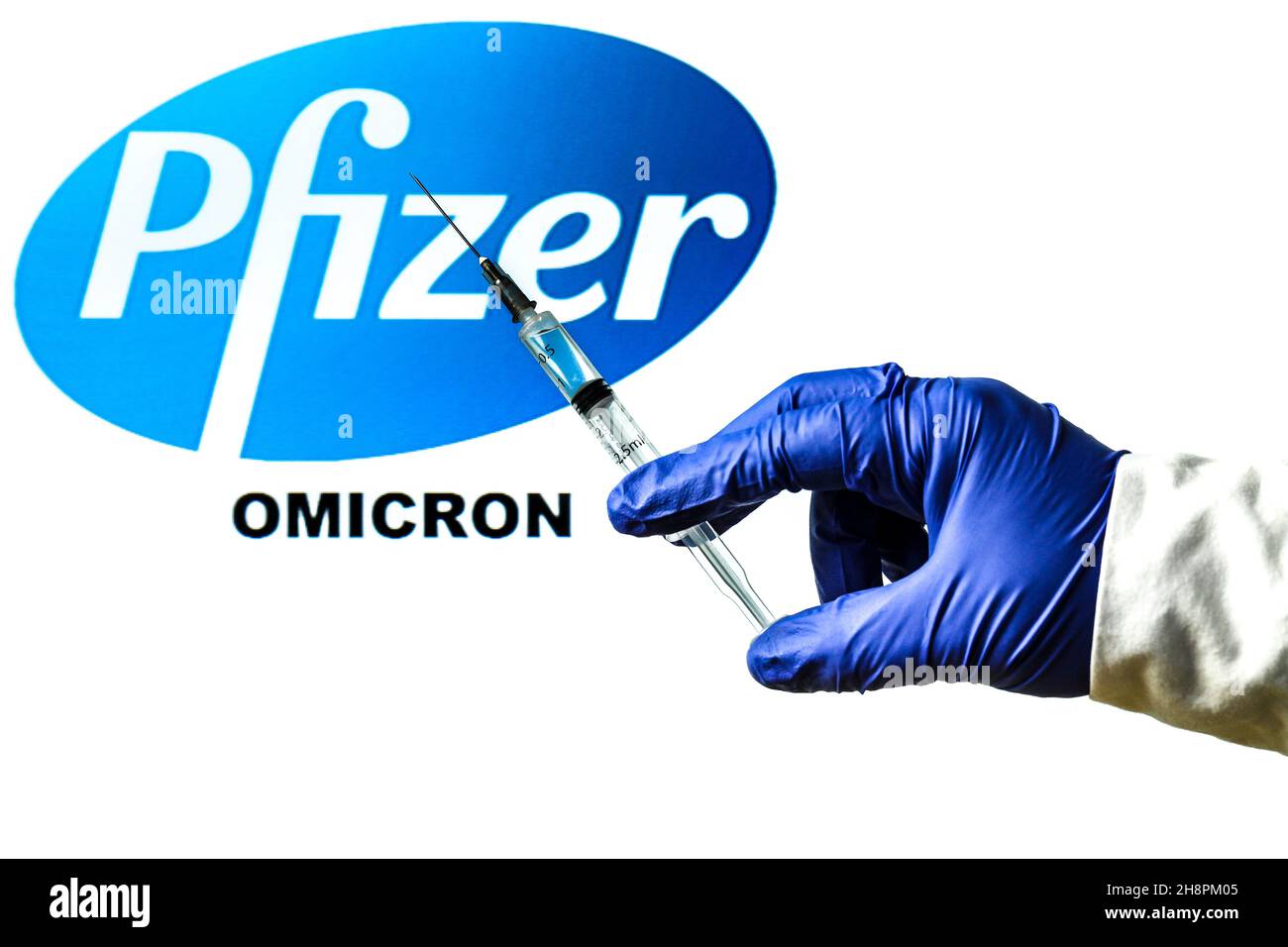Madrid, Spanien - 29. November 2021: Handhaltende Spritze mit Covid-19-Impfstoff und Pfizer-Logo und neuem Omicron-Wort auf weißem Hintergrund. Stockfoto
