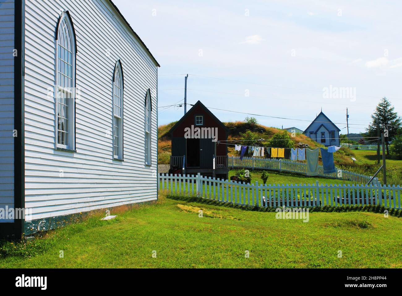 An der Seite einer Kirche entlang über den Kirchhof auf die Kleidung schauen, die auf einer Linie trocknet. Stockfoto