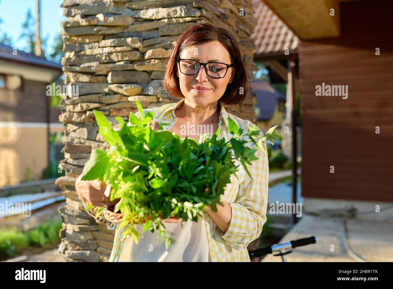 Frau im Garten hält Korb mit frisch gepflückten Ernte von grünen würzig duftenden Kräutern Stockfoto