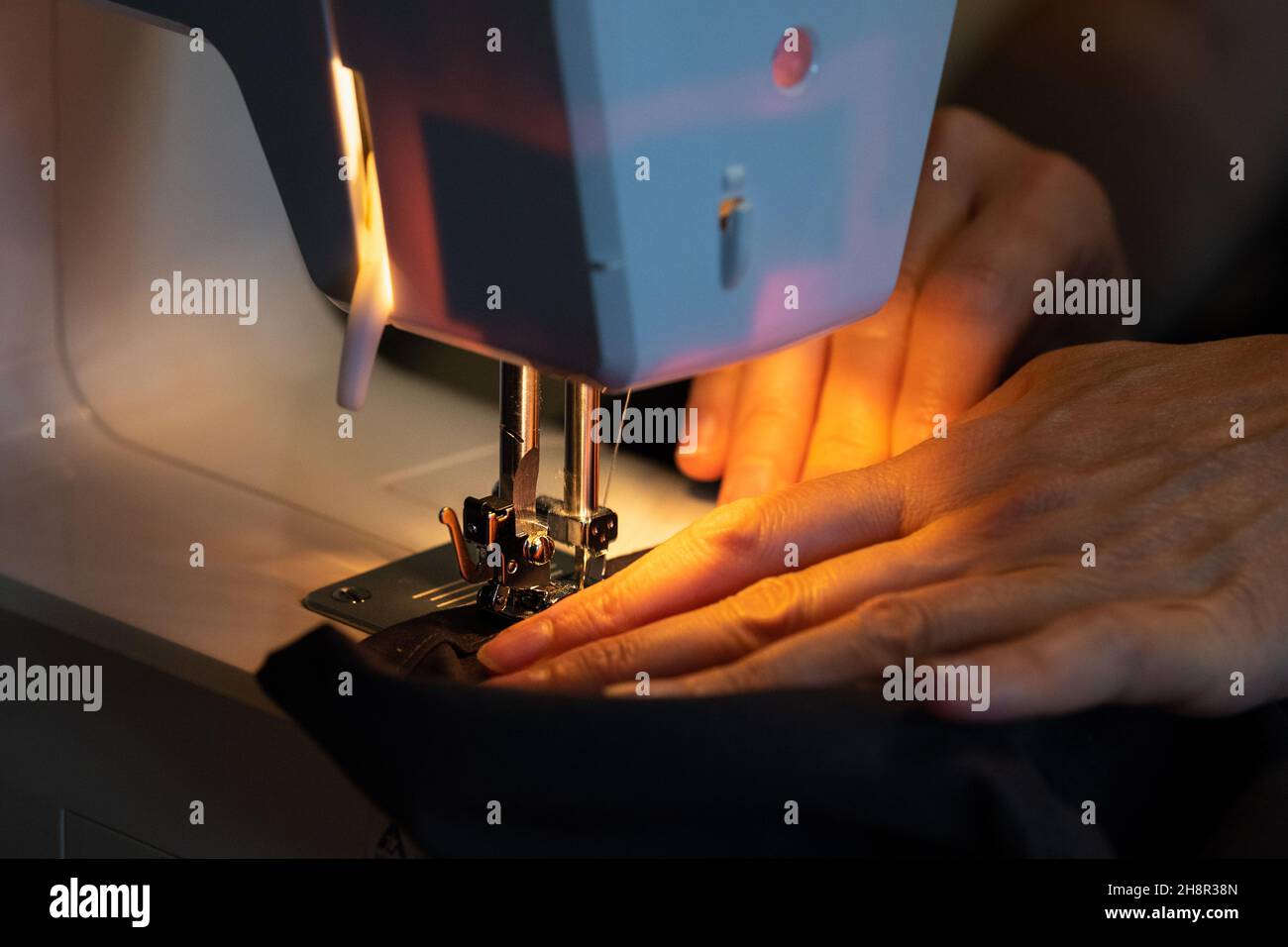 Die Hände der Frau nähen auf einer Nähmaschine, Nahaufnahme, Arbeitsprozess Stockfoto