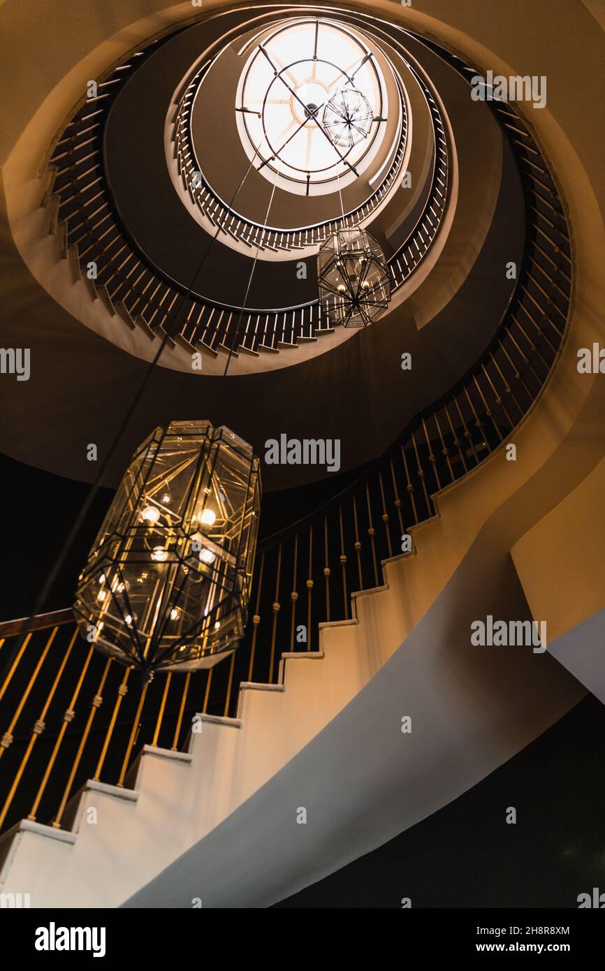 Gegenbild einer Wendeltreppe mit zwei großen Lampen in Gold- und Brauntönen. Stockfoto