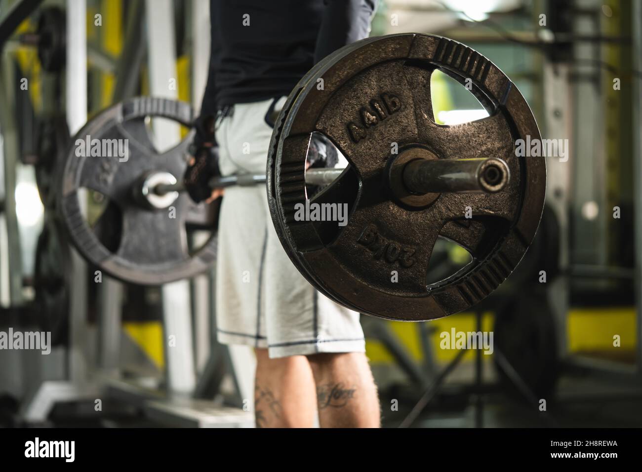 Seitenansicht eines unbekannten kaukasischen Mannes, der Hantelgewichtsgriff an Gewichten im Fitnessstudio hält, wenn er in der Totzugposition im Mittelteil des Fitnessraums den Kopierraum trainiert Stockfoto