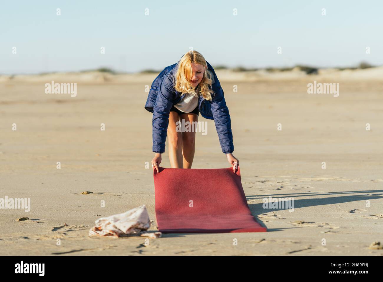 Frau, die am Strand eine Yogamatte ausrollt Stockfoto