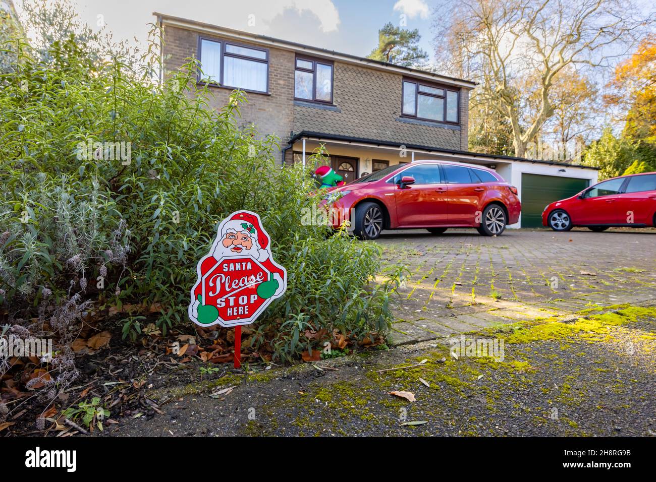 „Santa please stop here“ – festliches Novum-Zeichen für Weihnachten in einem Vorgarten vor einem Haus in Surrey im Dezember Stockfoto