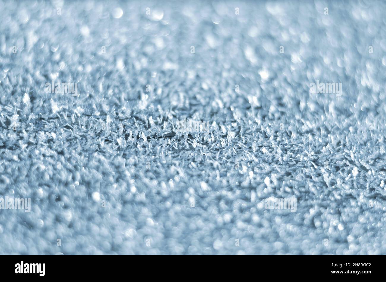Rime auf der Oberfläche als hellblauer Winterhintergrund mit Kopierraum. Sehr kurze Schärfentiefe. Stockfoto