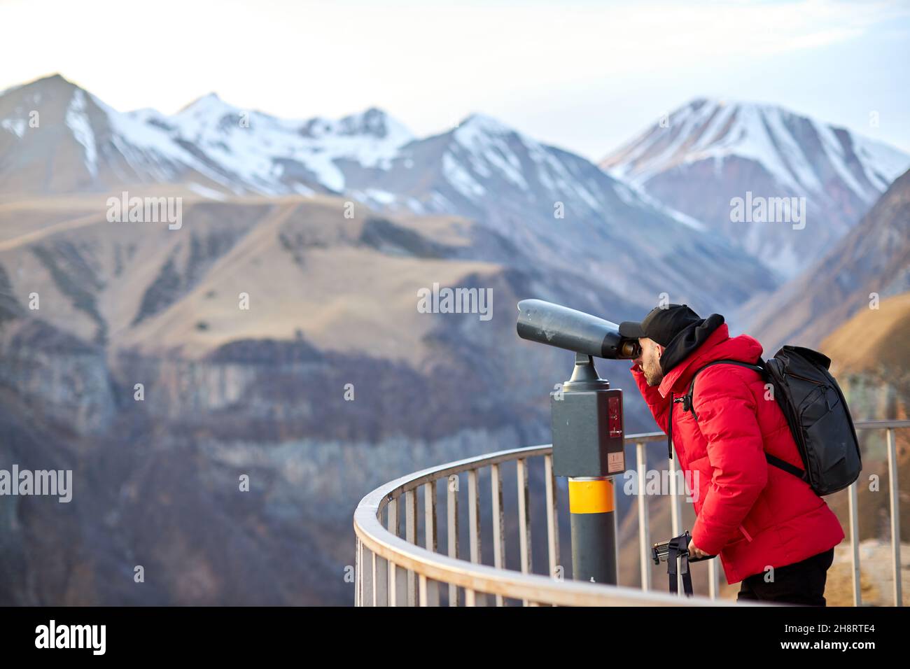 Mann mit schwarzem Rucksack auf Aussichtsplattform, Touristenreisender im Hintergrund Panoramablick auf die Berge Stockfoto