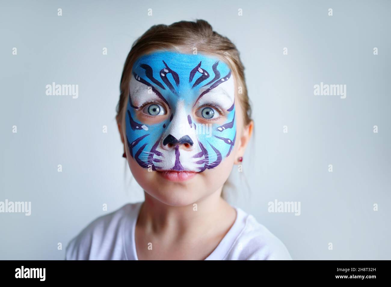 Mädchen Aqua Make-up in Form eines blauen Wassertiger Tierkreises auf weißem Hintergrund, Konzeptsymbol des neuen Jahres 2022, überraschte Porträt Stockfoto