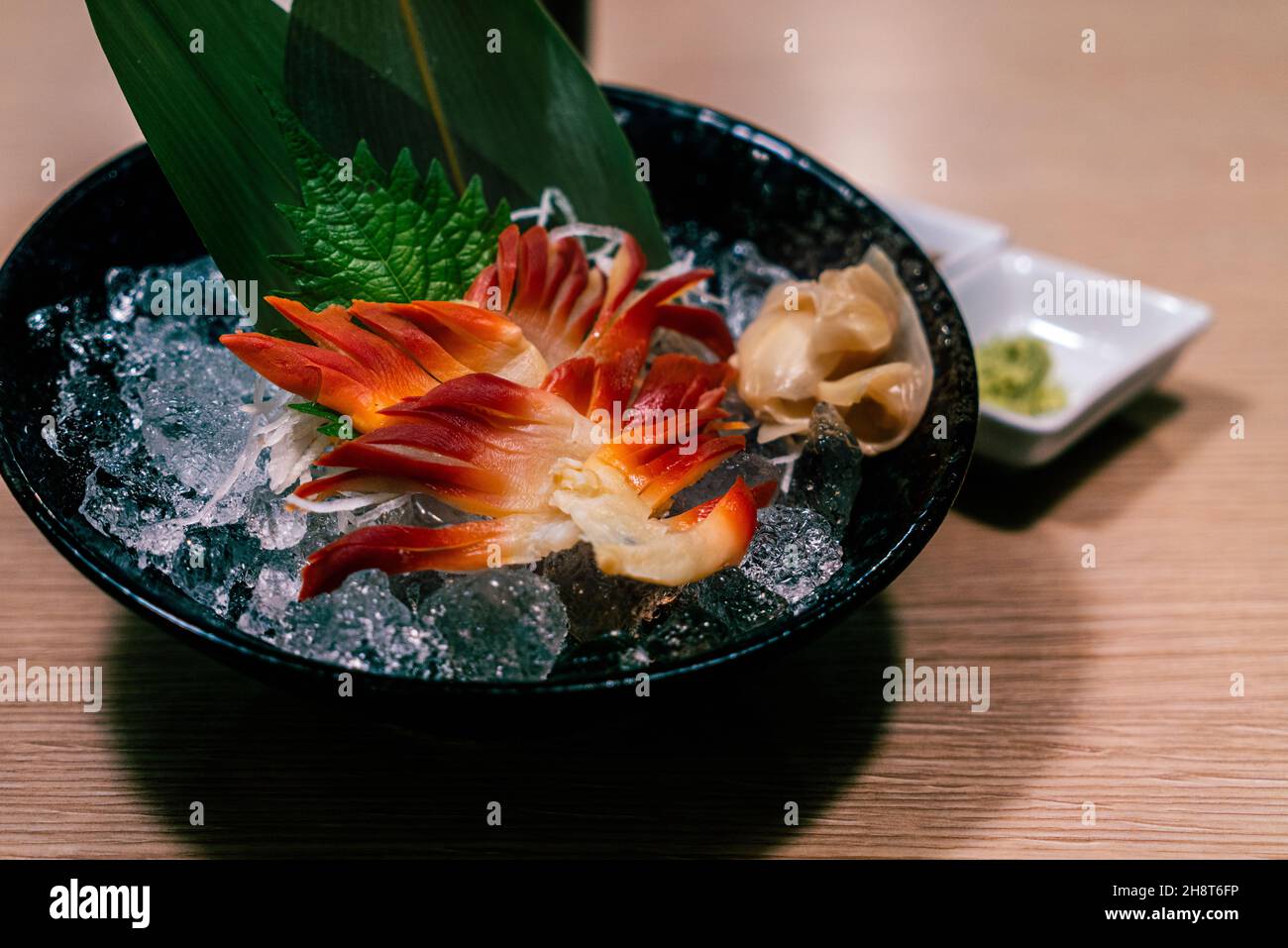 Japanische Stimpson Surf Clam oder Clam Ritzel oder hokkigai Sashimi mit Eis und Glas schwarzen Schale auf dem Tisch. Frische rohe Meeresfrüchte von japanischer gesunder Speisekarte. Stockfoto