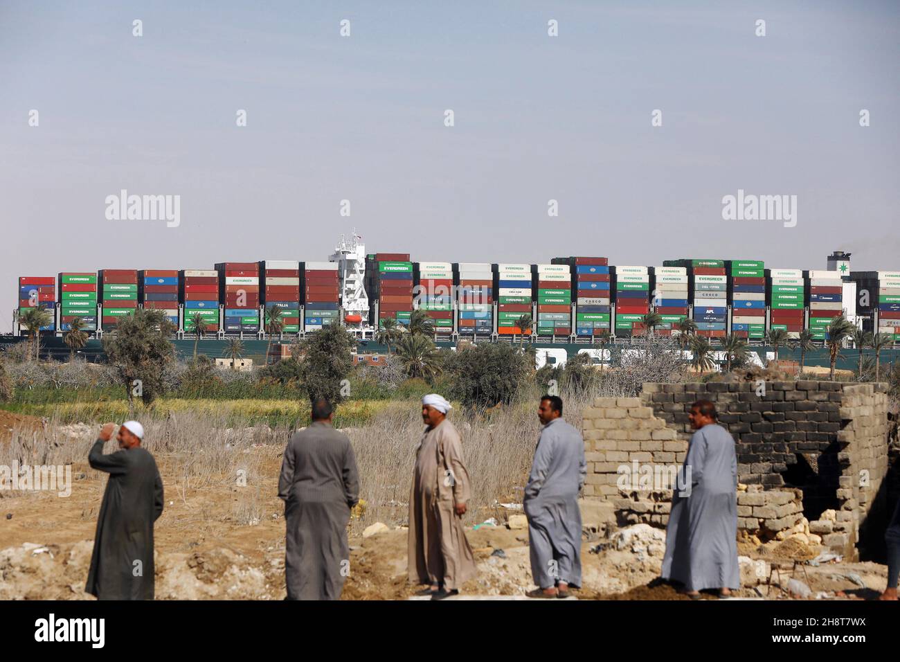 Suez, Ägypten. 02nd Dez 2021. Eine Gruppe ägyptischer Männer schaut auf das Containerschiff, das „jemals gegeben“ wurde, nachdem es am Montag, den 29. März 2021, vom Ufer des Suezkanals in Ägypten vertrieben wurde. Das Schiff, ein Megaschiff mit der Länge von vier Fußballfeldern, wurde wieder aufgeschwemmt und der Suezkanal wurde am Nachmittag wieder für den Verkehr geöffnet, was fast eine Woche nach dem Stau des riesigen Containerschiffes und der Blockade einer wichtigen Verkehrsader für den Welthandel zu einer Erleichterung wurde. Foto von Karem Ahmed/UPI Credit: UPI/Alamy Live News Stockfoto
