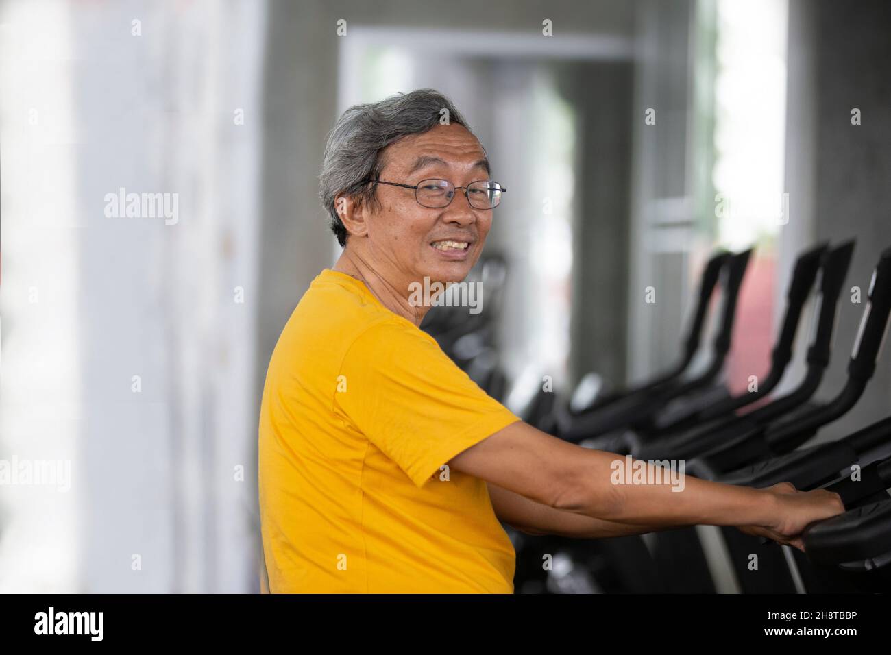 Porträt eines Senioren mit einer Brille, der im Fitnessstudio trainiert. Stockfoto