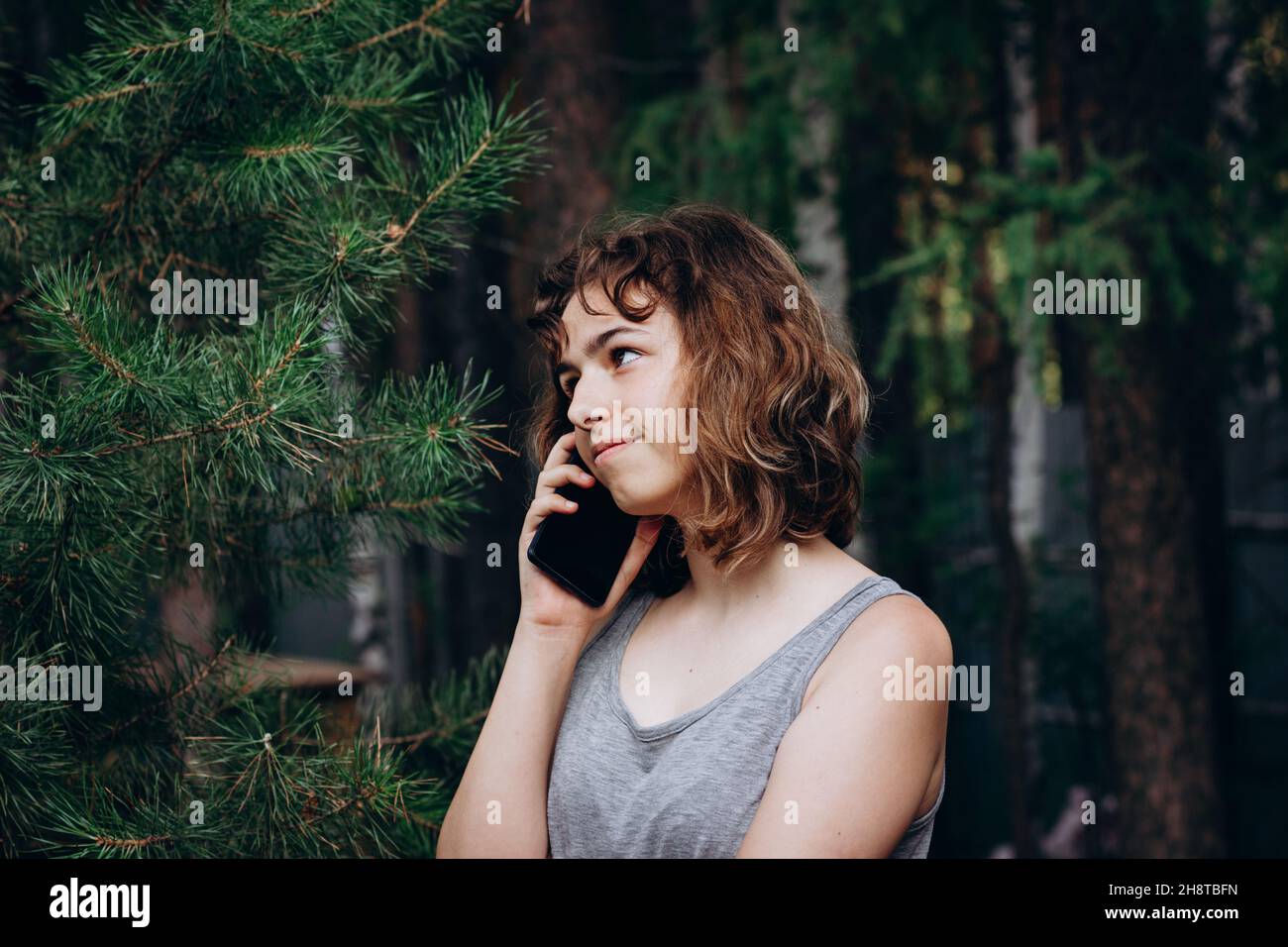 Schöne Teenager-Mädchen telefoniert im Wald. Stockfoto