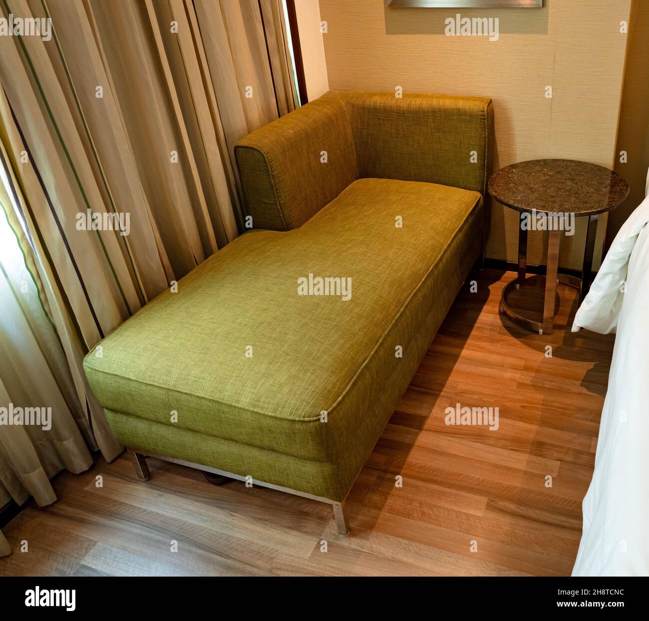 Ein grünes Luxus-Sofa im Wohnbereich in einem modernen Luxus-Hotelzimmer. Stockfoto