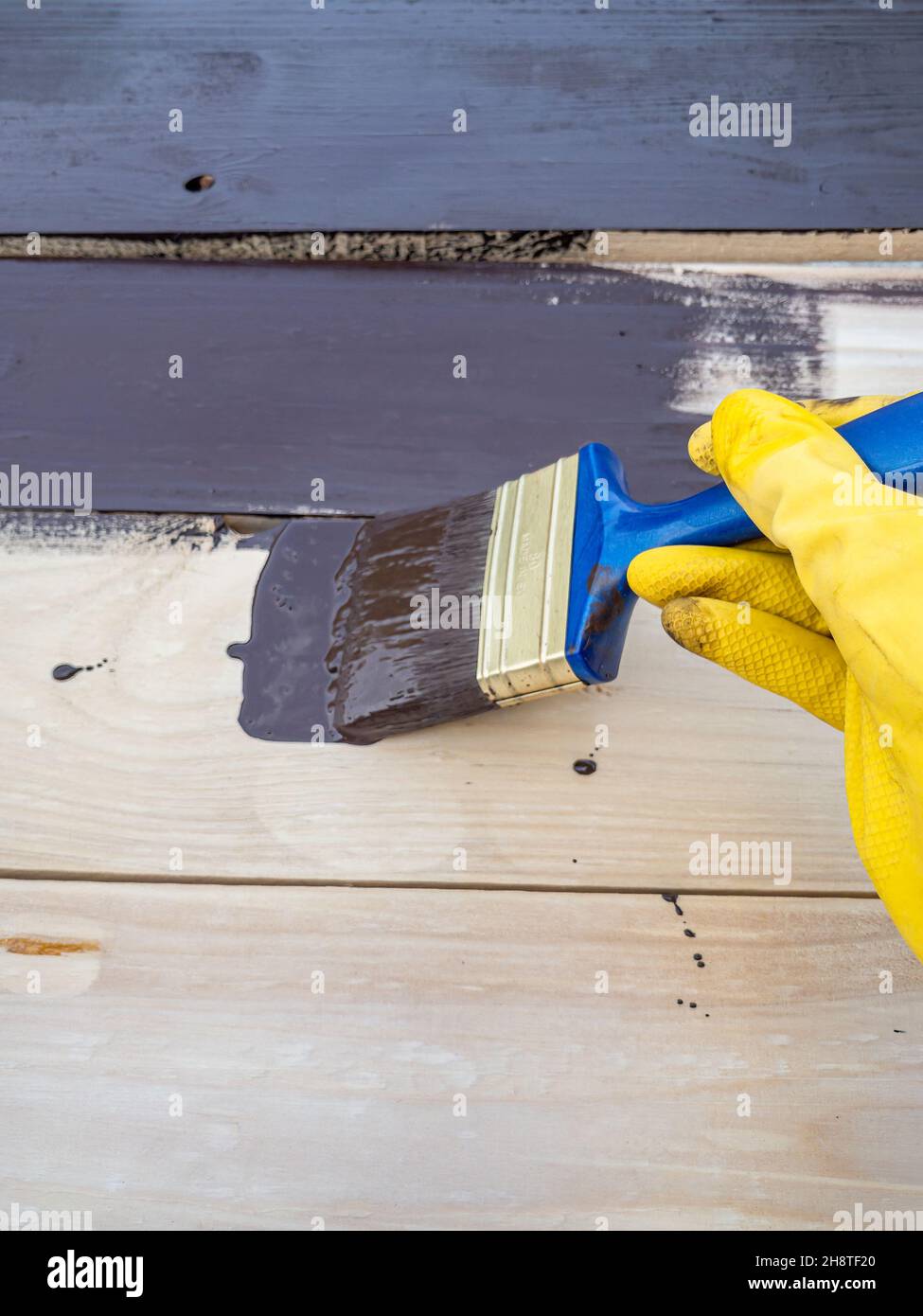 Ljubljana, Slowenien - 24. Juli 2021: Eine Frau hält einen Pinsel in der Hand und malt eine Planke mit dunkler schokoladenbrauner Farbe Stockfoto