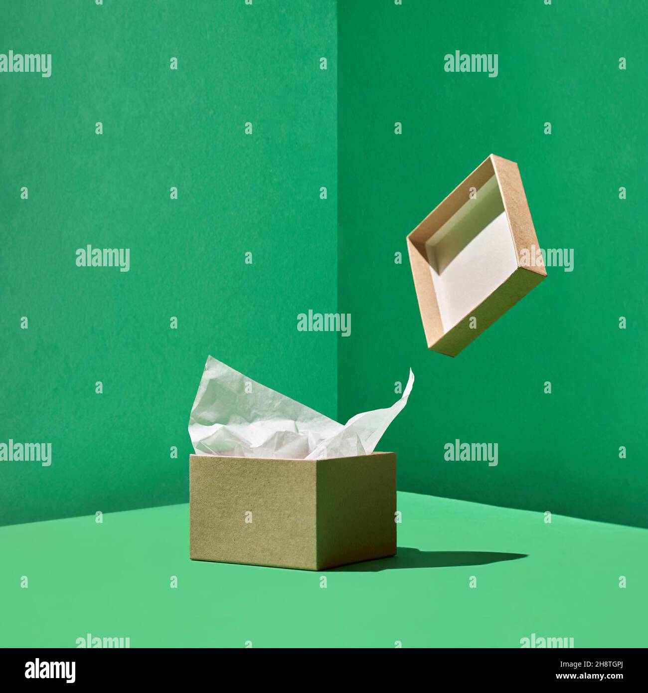 Bastelkiste mit Packpapier innen und levitierender Kiste Abdeckung auf grüner Rückseite Stockfoto
