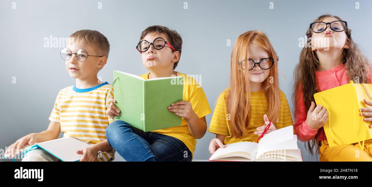 Gruppe von Kindern, die drinnen sitzen und Bücher lesen. Stockfoto