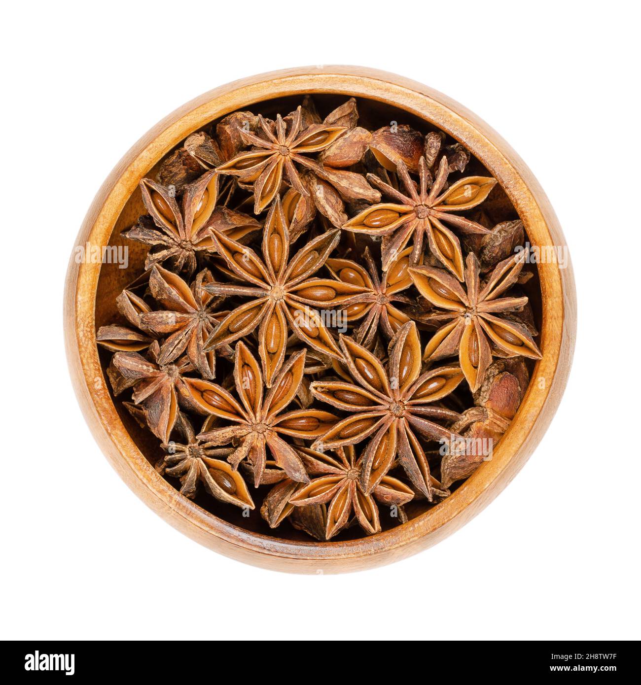 Sternanisfrüchte und Samen, in einer Holzschale. Auch bekannt als Staranise, Sternanis oder Badian. Getrocknete, sternförmige Perikarpfen von Illicium verum. Stockfoto