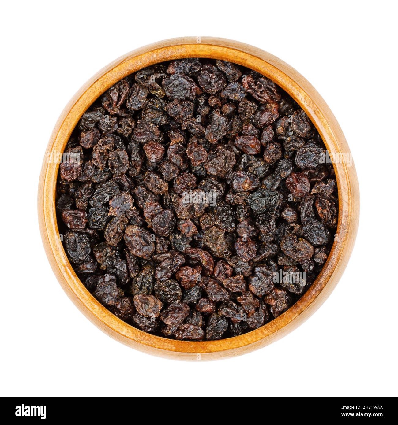 Zante Johannisbeeren, in einer Holzschale. Kleine Rosinen, auch als Corinth Rosinen oder einfach nur Johannisbeeren bekannt. Getrocknete Früchte der kleinen, süßen, kernlosen Trauben. Stockfoto