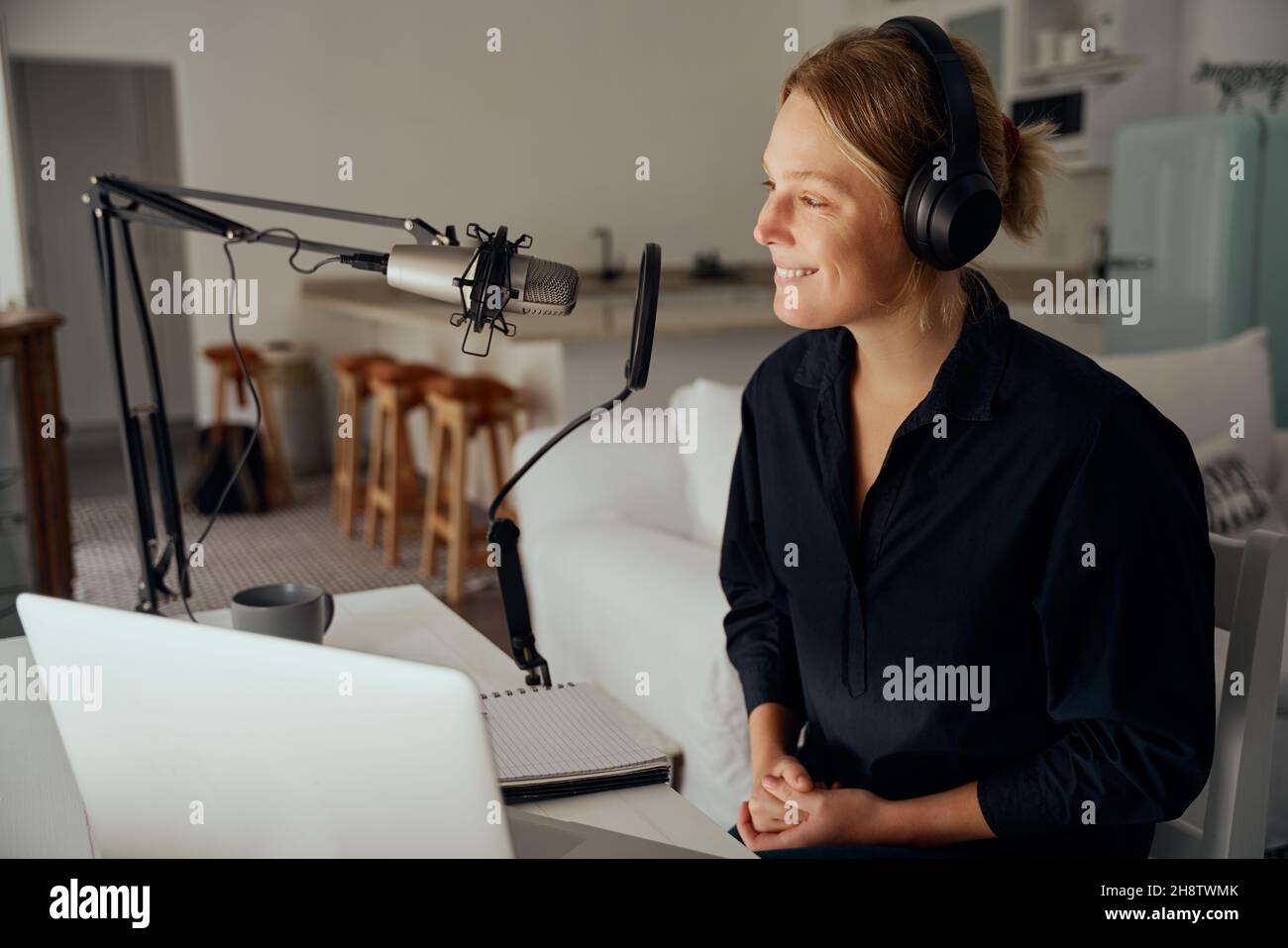 Kaukasische Frau, die von zu Hause aus Podcast im Wohnzimmer aufzeichnet Stockfoto