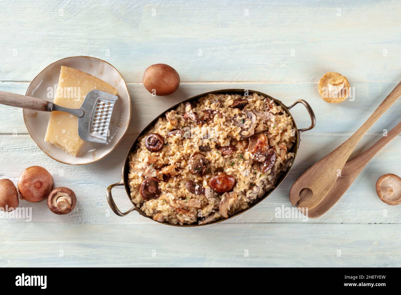 Pilzrisotto, rustikaler italienischer Reis mit Pilzen und Käse, mit Zutaten, Top Shot auf einem hölzernen Hintergrund Stockfoto