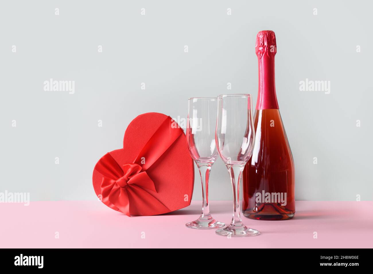 Valentinstag Komposition aus Champagner oder Sekt, Herz-Geschenkbox, Weingläser auf blauem Hintergrund. Grußkarte mit Kopierplatz. Stockfoto