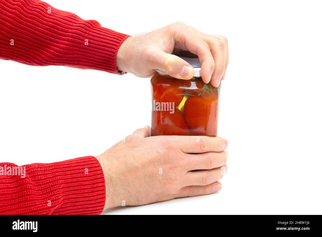 Ansicht der männlichen Hände, die ein Glas eingelegter Tomaten auf Weiß öffnen Stockfoto