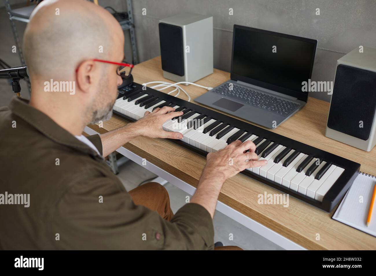 Ein Mann, der gerne Musik spielt, spielt auf einem modernen Synthesizer und schafft neue musikalische Kompositionen. Stockfoto