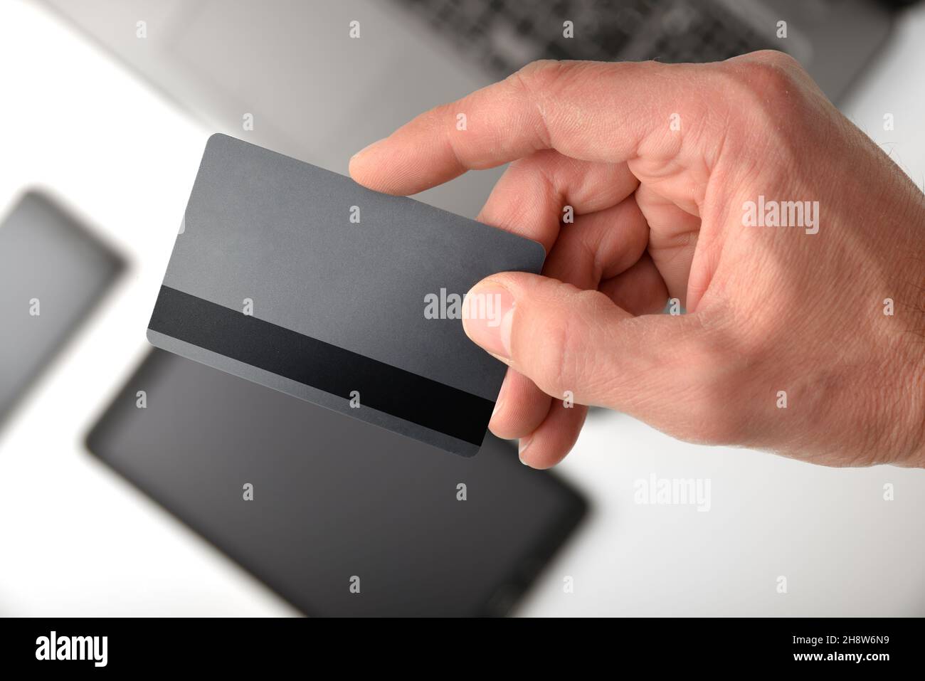 Elektronisches Zahlungskonzept mit einer Hand, die im Hintergrund die Kreditkarte mit mobilen Geräten anzeigt. Draufsicht. Stockfoto