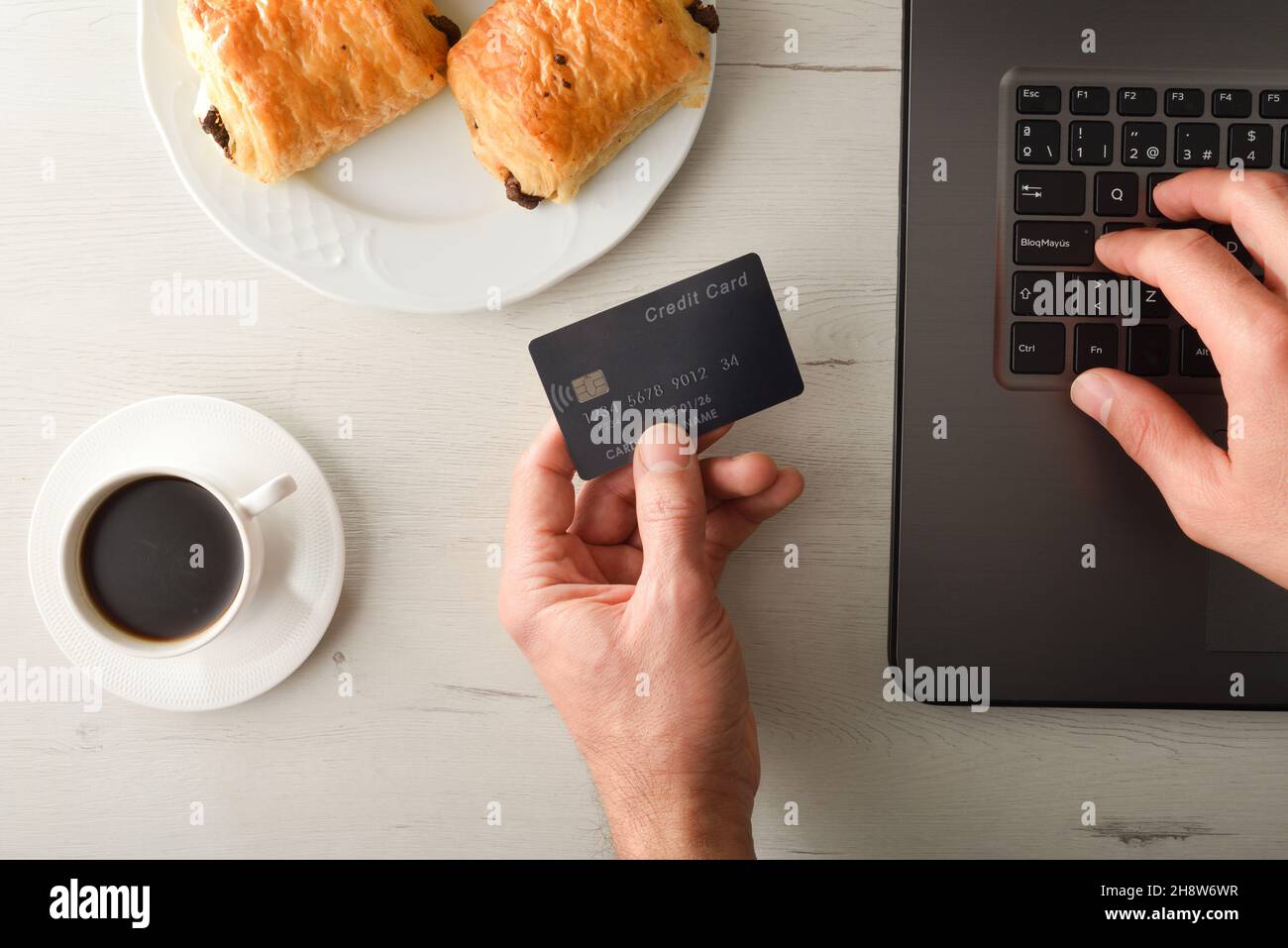 Online-Zahlung durch Eingabe von Kreditkartendaten in einem Laptop auf dem Tisch mit Frühstück. Draufsicht. Horizontale Zusammensetzung. Stockfoto
