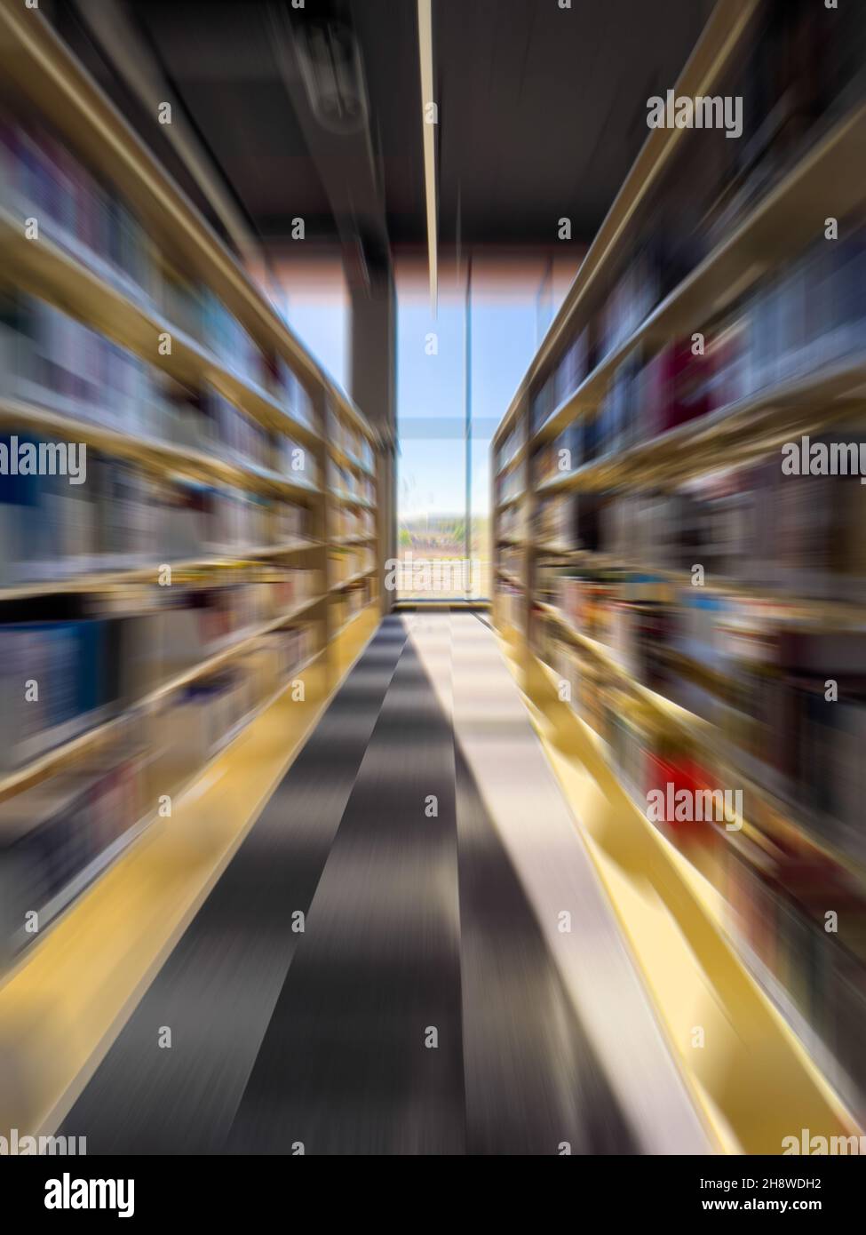 Verschwommene Zoomansicht des Korridors zwischen Bücherregalen in der Bibliothek Stockfoto