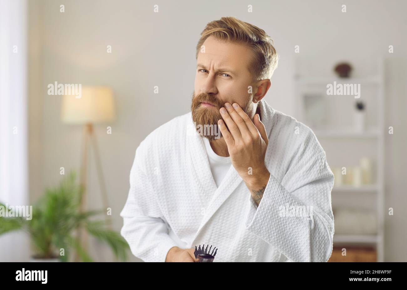 Besorgt schöner Mann Blick auf Falten auf seinem Gesicht während der morgendlichen Hautpflege Routine Stockfoto