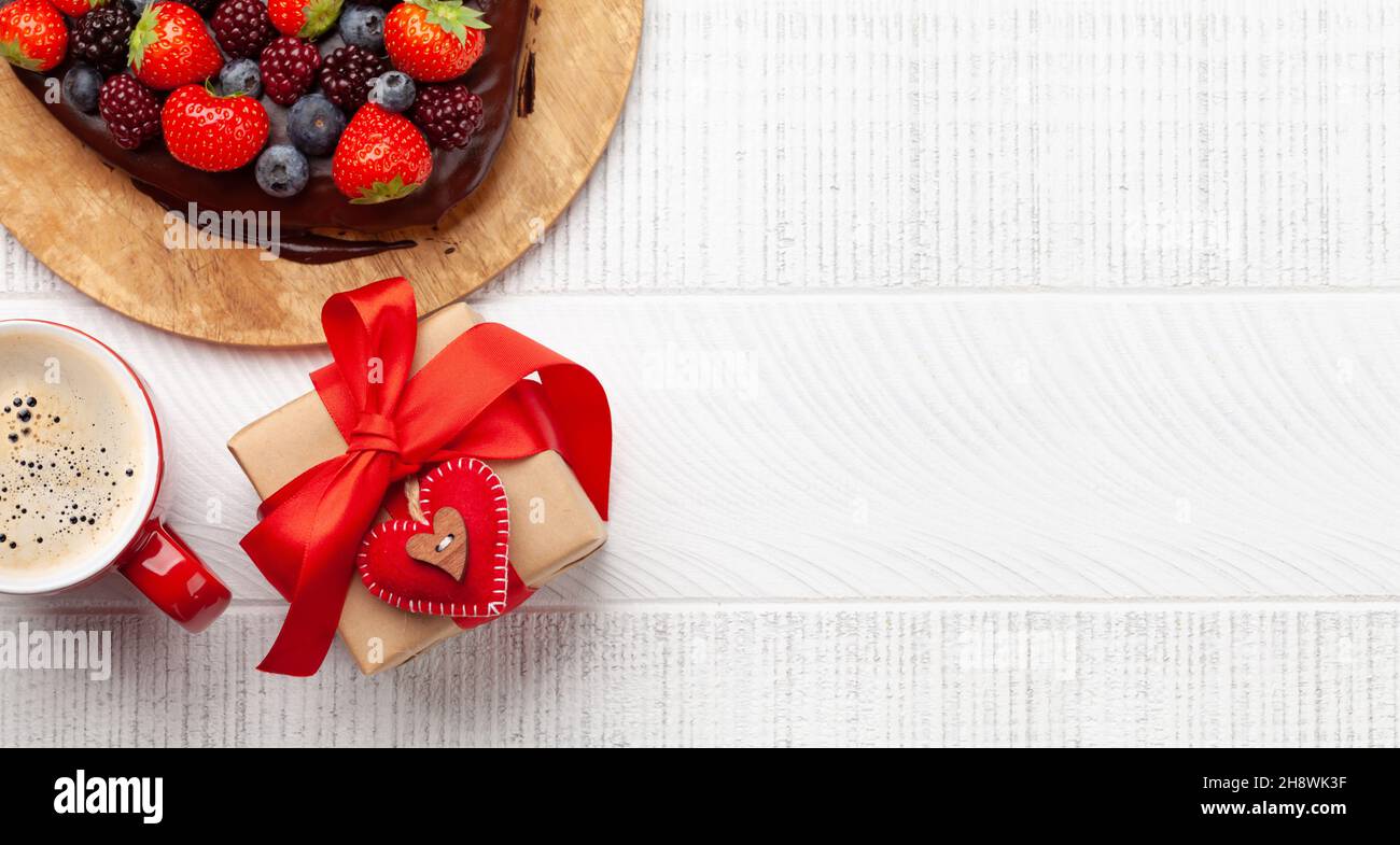 Herzförmiger süßer Kuchen mit Beeren, Kaffee und Geschenkbox. Grußkarte zum Valentinstag. Draufsicht flach liegend mit Kopierplatz Stockfoto