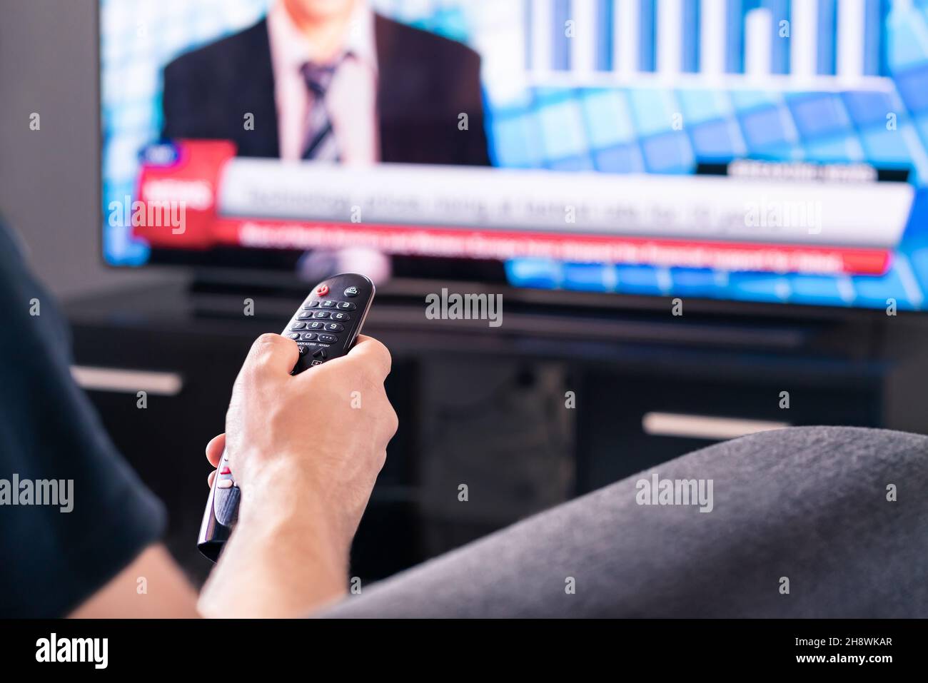 Aktuelle Nachrichten im fernsehen. Mann, der live Fernsehsendung ansieht. Covid19, Coronavirus und medizinische Informationen oder Wahlreporter. Stockfoto