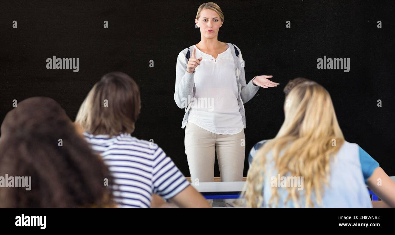 Lehrer gestikulierte, während er Erwachsene männliche und weibliche Schüler vor schwarzem Hintergrund erklärte Stockfoto