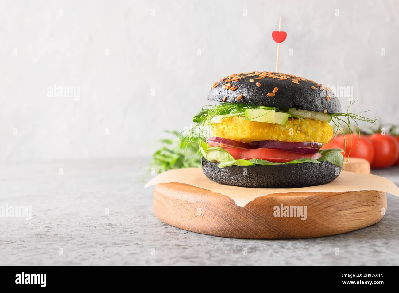Veganer Burger auf pflanzlicher Basis mit Gemüsefleischbällchen und schwarzen Kohlebuns auf grauem Hintergrund, mit Liebe hergestellt. Nahaufnahme. Gesundes Essen und Abendessen für VA Stockfoto