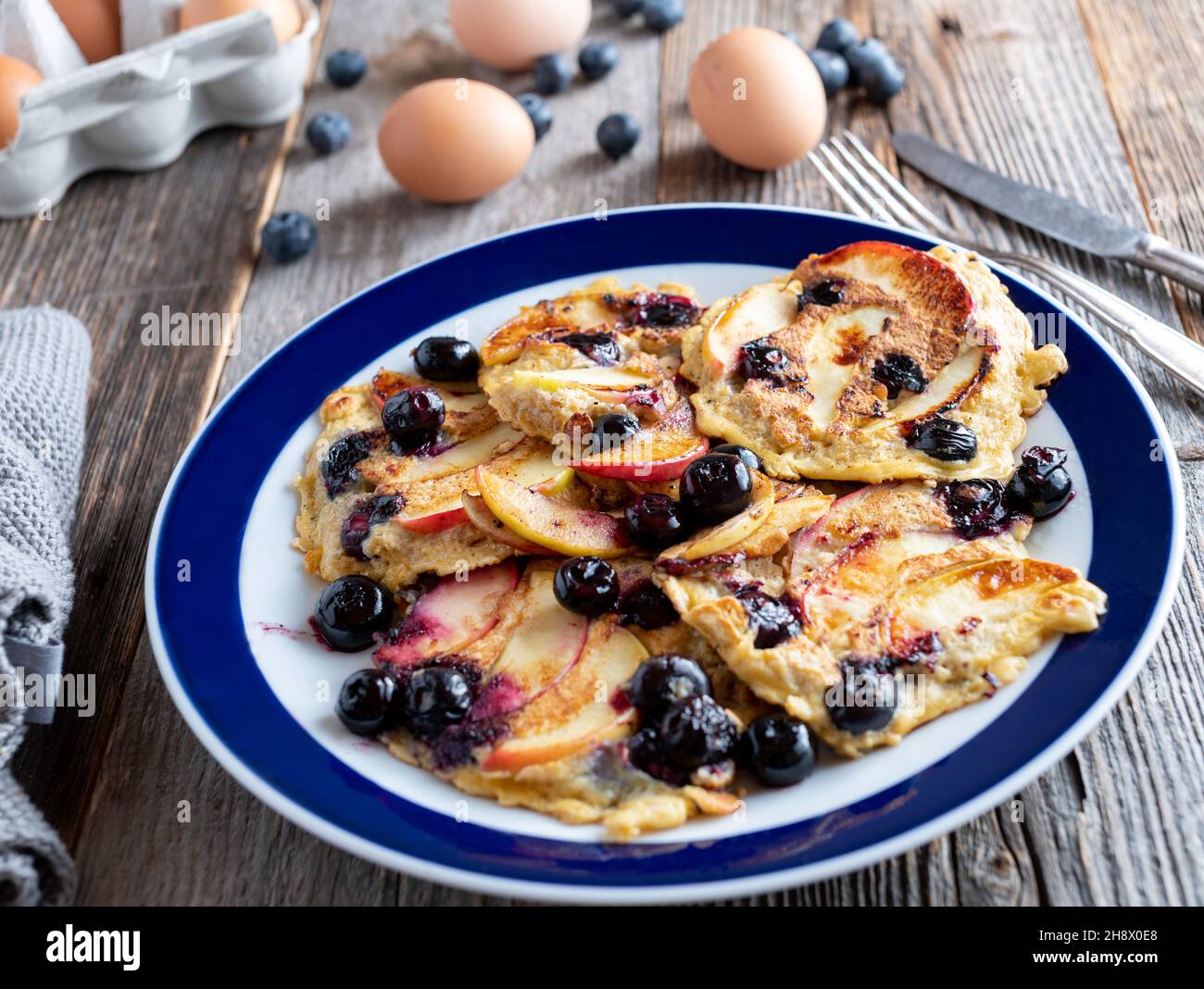 Fitness-Frühstück mit gebratenen Haferflocken-Pfannkuchen, Äpfeln und Heidelbeeren auf einem Teller Stockfoto