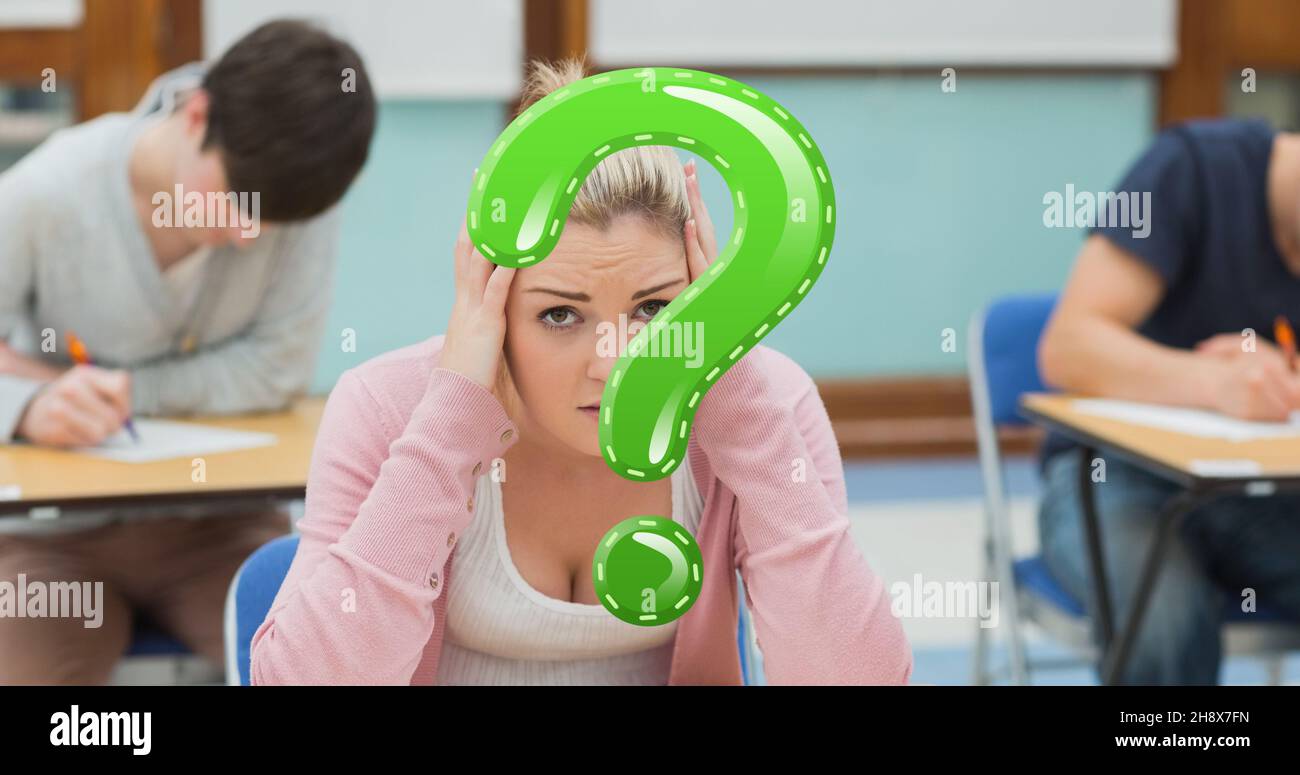 Digitaler Verbund aus grünem Fragezeichen über angespannter Studentinnen, die in der Prüfungshalle sitzen Stockfoto