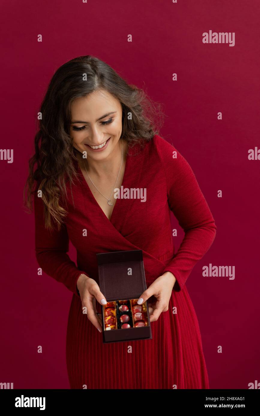 Schöne Emotion Frau in rotem Kleid geöffnet Box mit Bonbons. Stockfoto